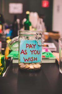 Image: Open mason jar with coins and "Pay as you wish" note inside
