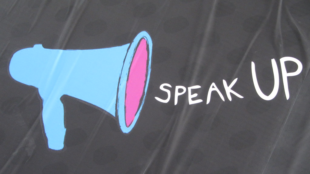 Image of a dark sheet with a blue megaphone and the words Speak Up drawn on it.