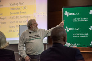 Image: Bill black pointing to a slide while discussing fraud.