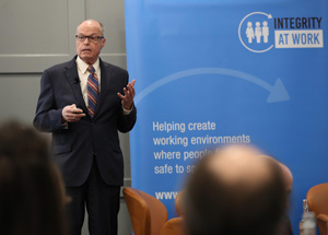 Richard Bowen presenting in front of a blue sign.