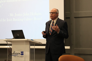 Picture of Richard Bowen presenting near a podium with a projected slide over his right shoulder.