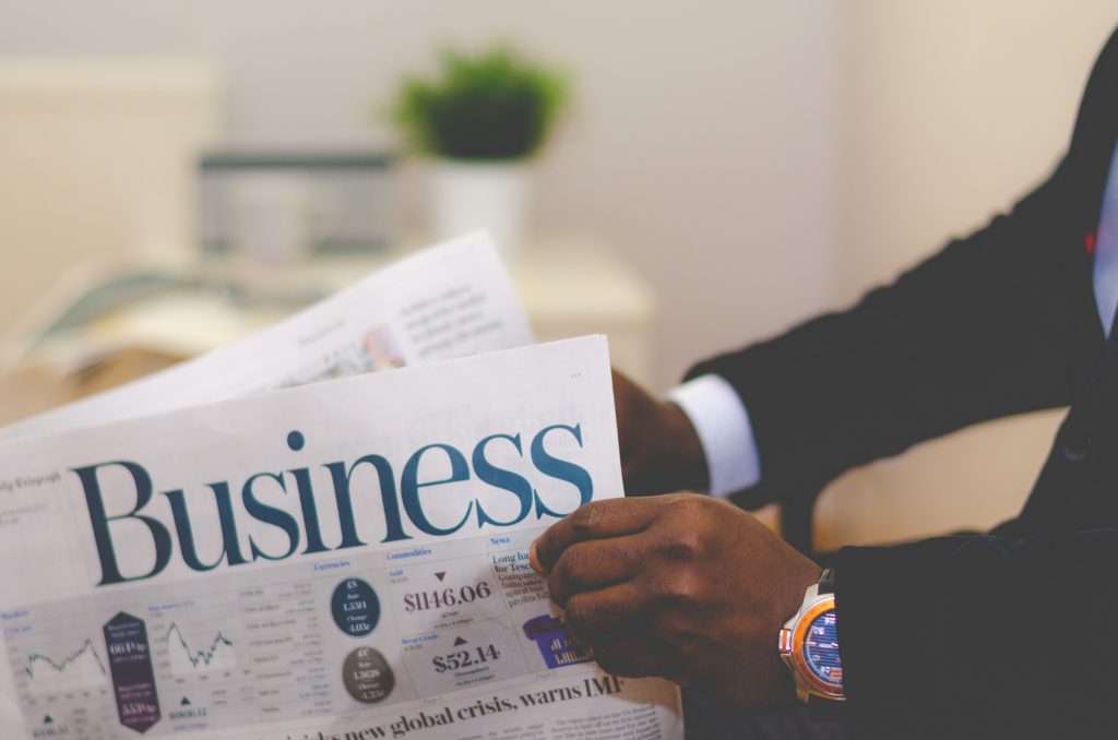 Image: man in suite holding Business section of a newspaper