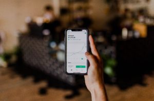 Image: Hand holding iPhone with stock market screen.