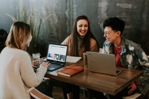 Women laughing and working on laptops together