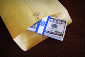 Image: Envelope with stack of $100 bills exposed.