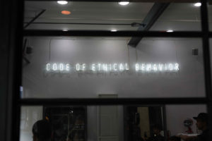Image: neon storefront sign that reads: Code of ethical behavior"